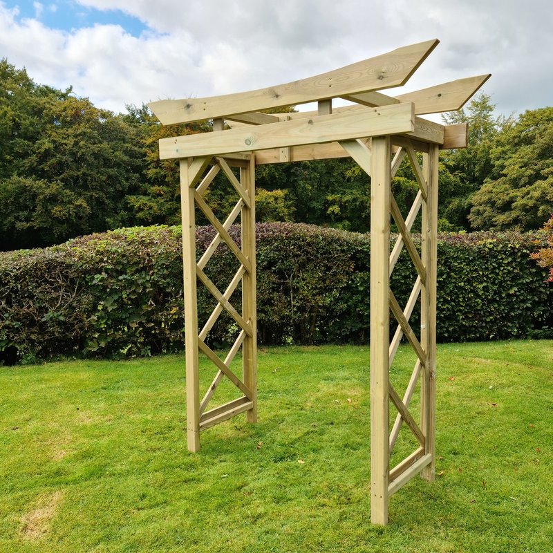 Wooden garden archway on a grassy area with trees in the background